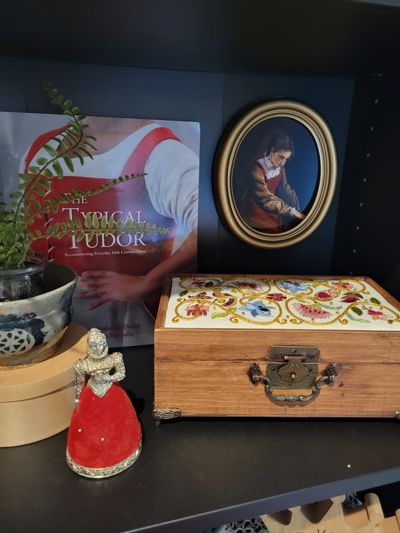 Box on shelf of historical costume objects.