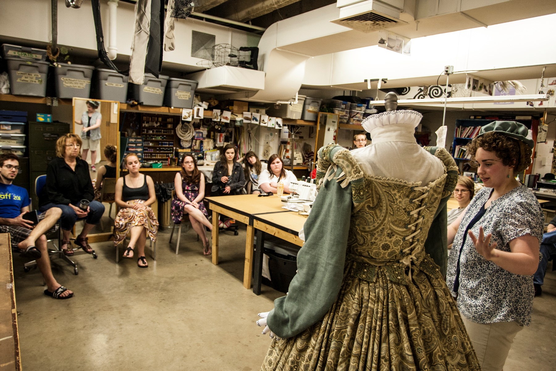 Emily stands by a mannequin wearing the gown, speaking to a group of people.