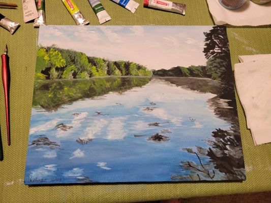 Painting freshly finished on table surrounded by paint tubes.