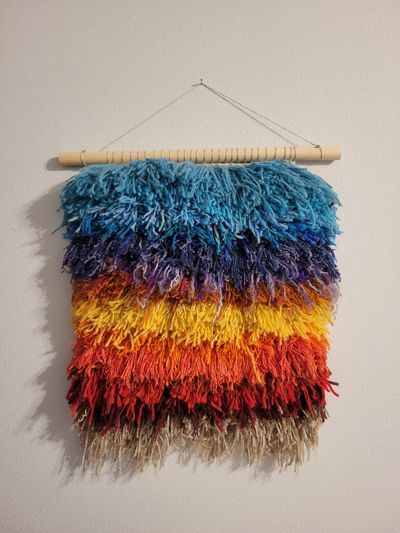 Shaggy woven wall hanging in sunset colors.
